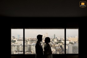 At Asia Hotel Bangkok, the silhouetted couple stands close together, their outlines softly lit to emphasize romance and movement within the reception space.